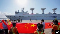 资料照：斯里兰卡港口工人在中国一带一路项目汉班托塔港手持中国国旗欢迎一艘装载着检测设备的中国考察船到港。（2022年8月16日）