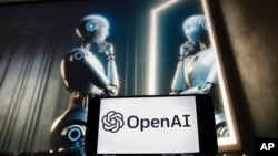 FILE - The OpenAI logo is seen displayed on a cellphone with an image on a computer monitor generated by ChatGPT's Dall-E text-to-image model in Boston, Massachusetts, Dec. 8, 2023.