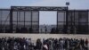 Un grupo de migrantes aguarda en Ciudad Juárez, México, junto al muro fronterizo con la esperanza de poder entrar en Estados Unidos el 30 de marzo de 2023.