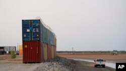 Agentes de la patrulla fronteriza patrullan junto a una hilera de contenedores de mercancías apilados cerca de la frontera, el martes 23 de agosto de 2022 cerca de Yuma, Arizona. Foto AP.