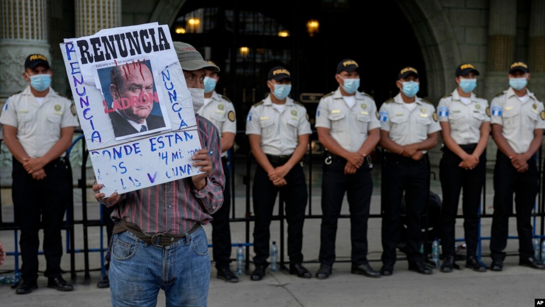 ARCHIVO. Un manifestante sostiene un cartel con un retrato del presidente guatemalteco Alejandro Giammattei frente al Palacio Nacional mientras la gente asiste a una manifestación en apoyo del fiscal anticorrupción Juan Francisco Sandoval, en Ciudad de Guatemala.