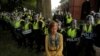Una manifestante parada frente a oficiales de policía del estado de Virginia que forman un cordón en la Universidad de Virginia, antes del primer aniversario de las protestas de Charlottesville 2017 "Unite the Right", en Charlottesville, Virginia, el 11 de agosto de 2018.