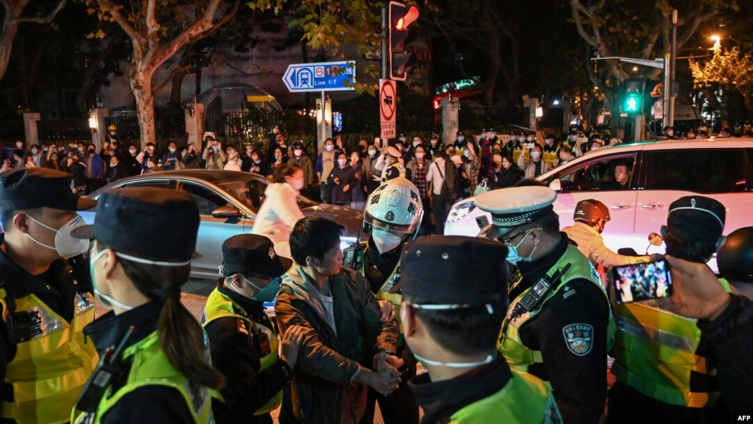 2022年11月27日，在上海烏魯木齊路舉行抗議的人群與警察。（法新社）