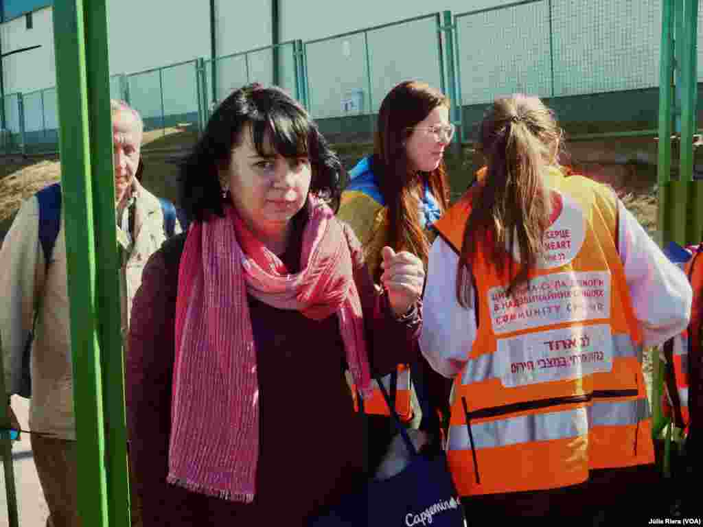 Refugiada ucraniana llega a Medyka. A su derecha, voluntarios se organizan para asistir a los refugiados. Muchos de los refugiados cruzan la frontera tras días de viaje. 