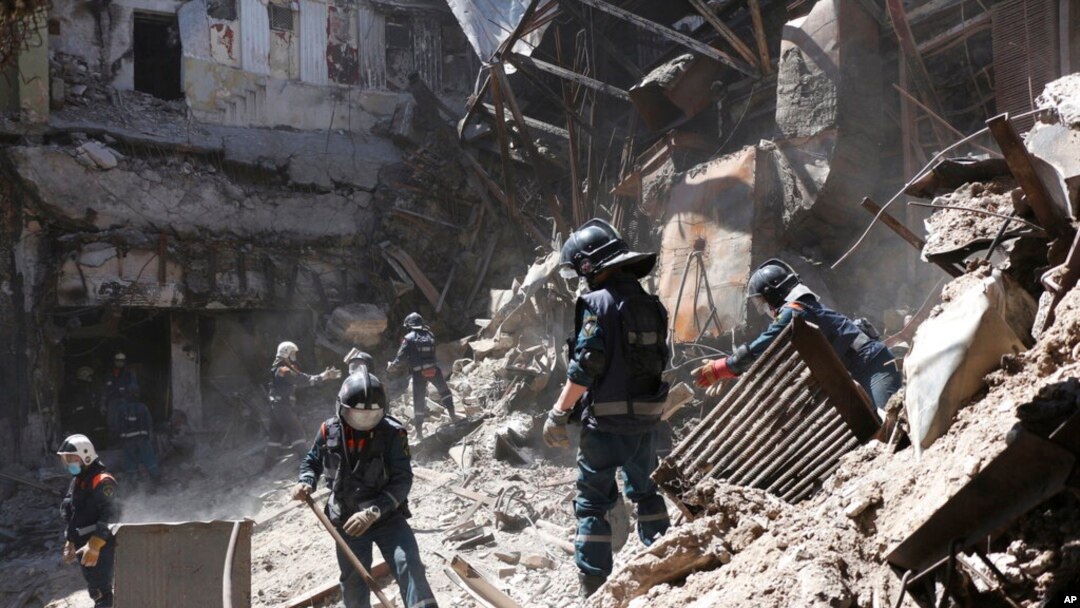 Empleados del Ministerio de Situaciones de Emergencia de la República Popular de Donetsk limpian los escombros al costado del edificio del teatro Mariupol dañado durante los intensos combates en Mariupol, en territorio bajo el gobierno de la República Popular de Donetsk, este de Ucrania, el 1 de mayo de 2022.