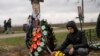 ARCHIVO - Yura Nechyporenko, de 14 años, coloca un chocolate en la tumba de su padre Ruslan Nechyporenko en el cementerio de Bucha, en las afueras de Kiev, Ucrania, el 21 de abril de 2022.