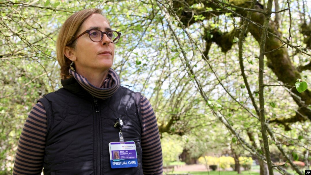 Rev. Jo Laurence, a Buddhist chaplain, poses for a photo on April 22, 2022 in the garden of a memory care facility in Portland, Ore. before visiting hospice patients to offer spiritual care. (AP Photo/Gosia Wozniacka) 