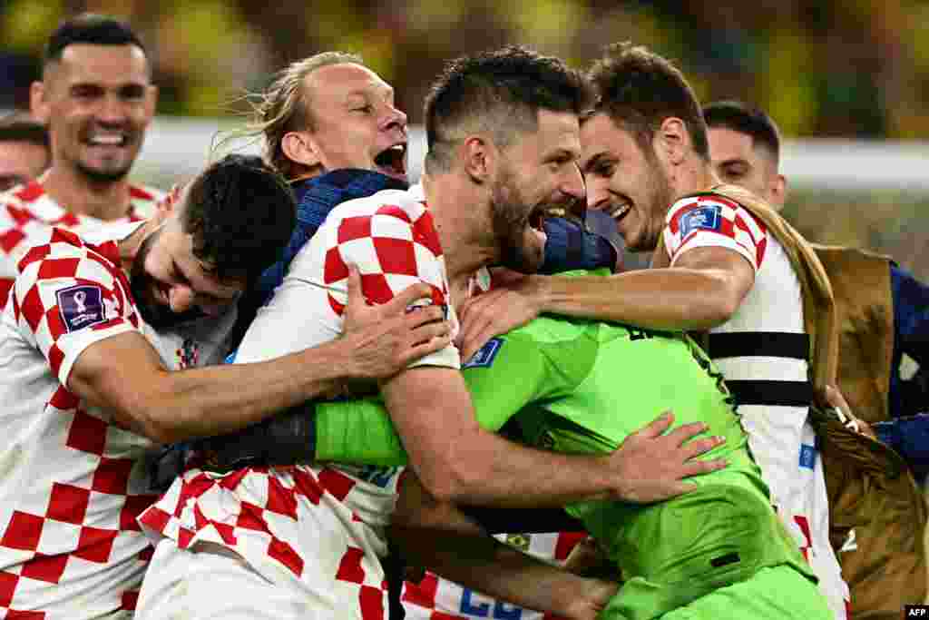 Bruno Petkovic e guarda-redes da Croácia, Dominik Livakovic, são abraçados por outros colegas depois da vitória frente ao Brasil.