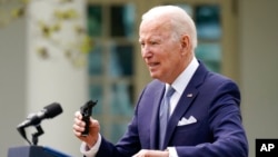 El presidente Joe Biden sostiene piezas de una pistola de 9 mm mientras habla en el Rose Garden de la Casa Blanca, en Washington DC, el 11 de abril de 2022.