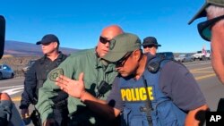 Police assemble near demonstrators blocking a road at the base of Hawaii's tallest mountain, Mauna Kea, Monday, July 15, 2019, on Hawaii's Big Island.