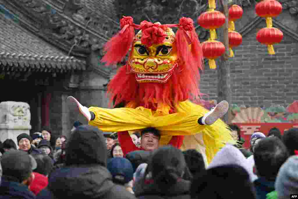 People watch lion dancers as they perform at a temple fair on the third day of the Lunar New Year of the Snake in China's capital, Beijing.