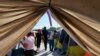 Migrantes caminan junto a sus tiendas de campaña en el refugio Senda de Vida 2 en Reynosa, México, el 15 de diciembre de 2022.