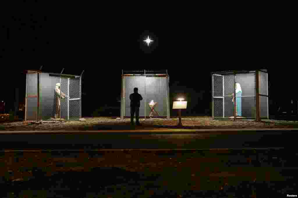 A man view sculptures of Jesus, Mary and Joseph, depicted as refugees in cages, at a Nativity scene at Claremont United Methodist Church in Claremont, California, Dec. 9, 2019.
