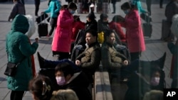 Viajeros con su equipaje esperan sus trenes afuera de la estación de trenes Oeste en Beijing, el sábado 3 de febrero de 2024. Se espera que millones de chinos viajen durante el período de vacaciones del Año Nuevo Lunar.