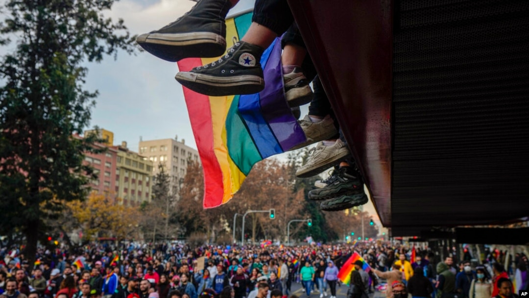 Los pies de los adolescentes cuelgan de un balcón mientras ven pasar el desfile anual del Orgullo Gay en Santiago, Chile, el 25 de junio de 2022. 