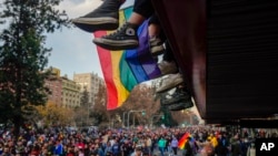 Los pies de los adolescentes cuelgan de un balcón mientras ven pasar el desfile anual del Orgullo Gay en Santiago, Chile, el 25 de junio de 2022. 