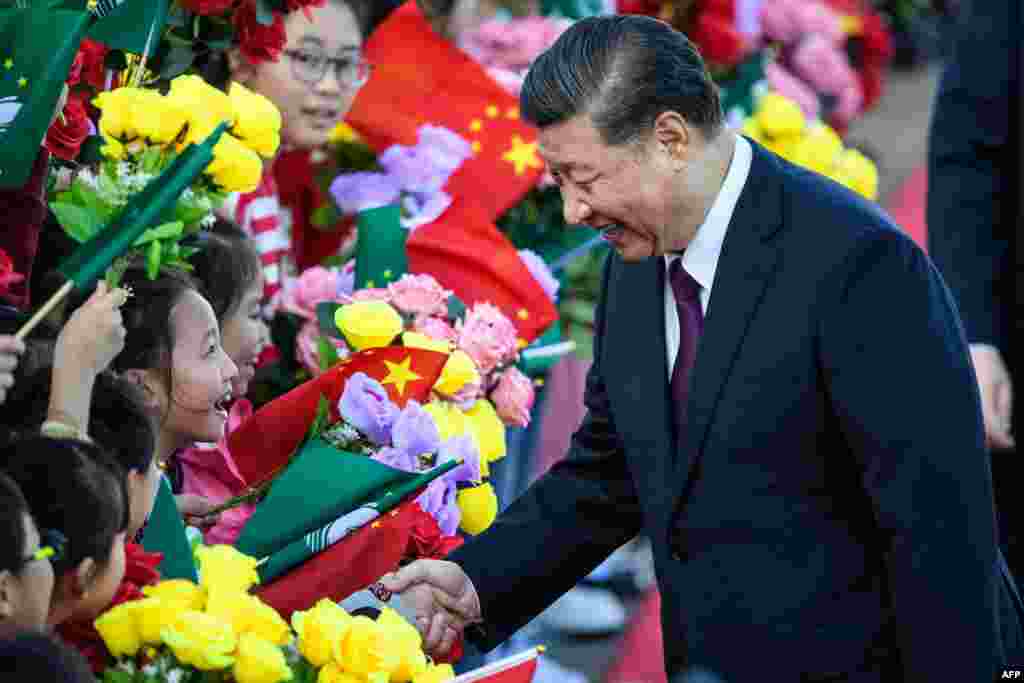 China's President Xi Jinping, right, shakes hands with a girl as she and other children welcome Xi upon his arrival at Macau's international airport in Macau.