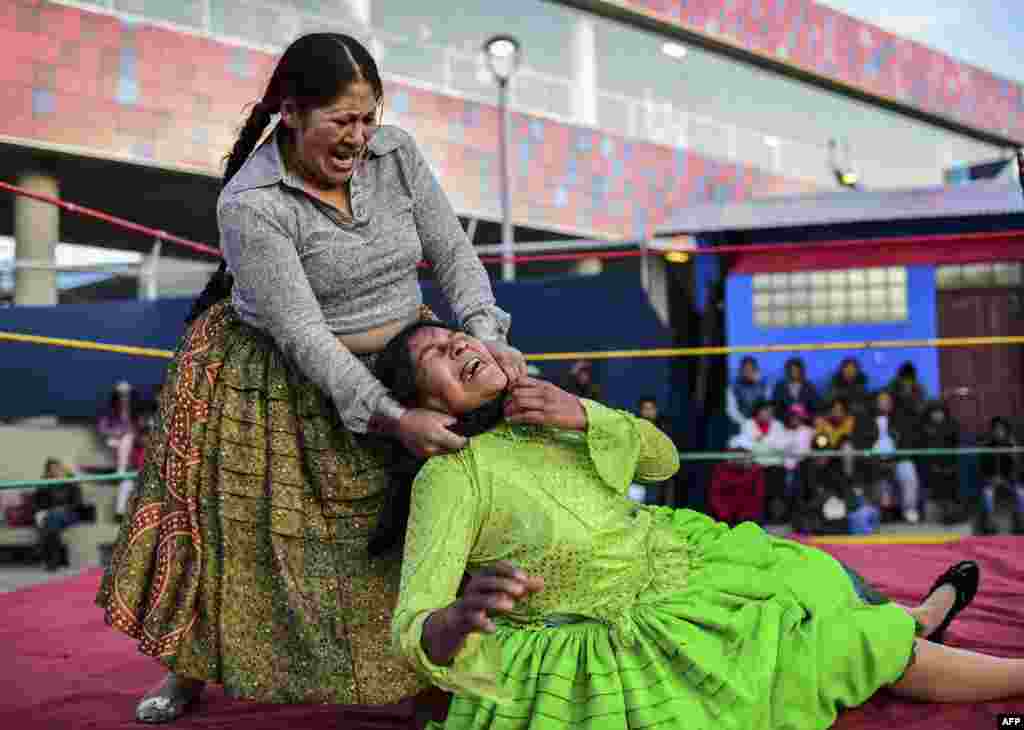 Bolivian wrestlers Ana Luisa Yujra (L), aka "Jhenifer Two Faces" and Lidia Flores, aka "Dina, The Queen of the Ring", both members of the Fighting Cholitas, fight at Sharks of the Ring wrestling club in El Alto.