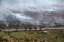 Wooden houses are pictured as smoke from forest fires envelops trees near Banjarmasin in South Kalimantan province, Indonesia, March 21, 2021.