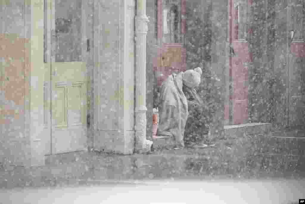 A homeless man sits in a doorway as snow falls in the French Quarter in New Orleans, Louisiana. A rare winter storm is charging through Texas and the northern Gulf Coast, blanketing New Orleans and Houston with snow, closing highways and grounding nearly all flights.