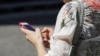 FILE - In this April 8, 2019, photo, a woman browses her smartphone. For many journalists working in Myanmar, the smartphone is a lifeline.