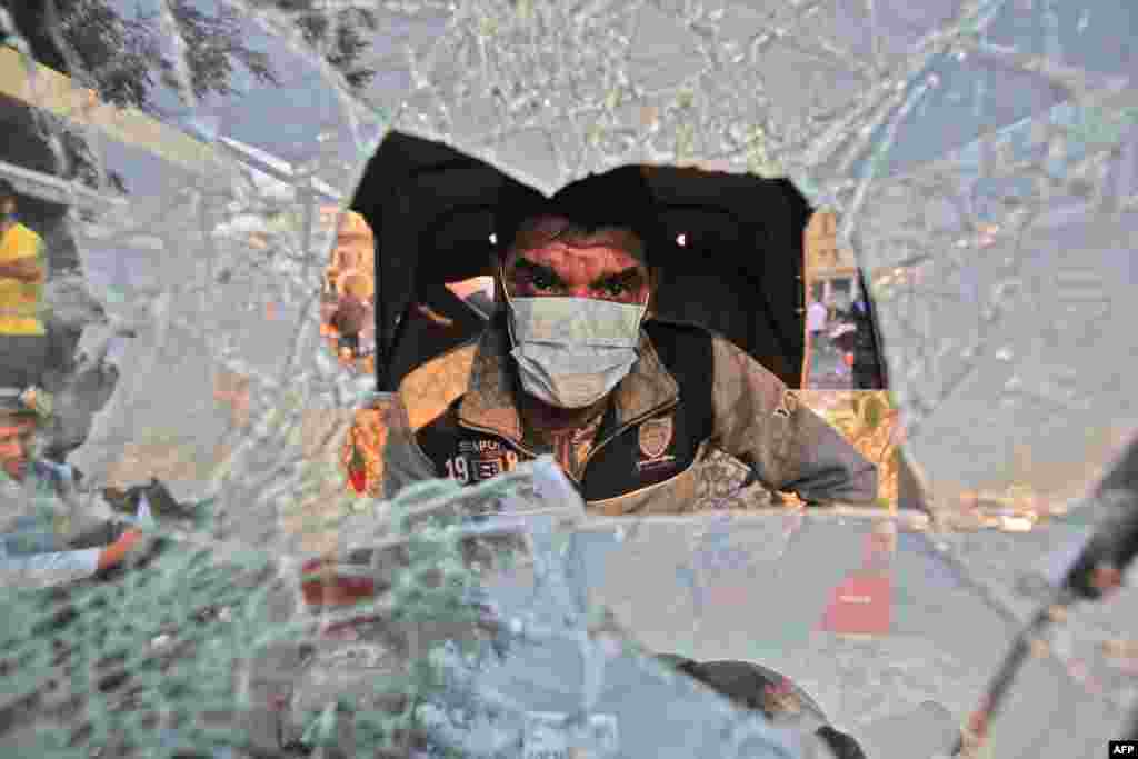 A tuktuk (motorized rickshaw) driver sits behind his broken windshield in his vehicle during clashes between anti-government protesters and security forces in the Iraqi capital Baghdad's Rasheed street near al-Ahrar bridge.