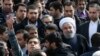 An Iranian man, at left, takes a selfie while trying to have President Hassan Rouhani, right with white turban, in his picture in a rally commemorating the 37th anniversary of the Islamic revolution, in Tehran, Feb. 11, 2016.