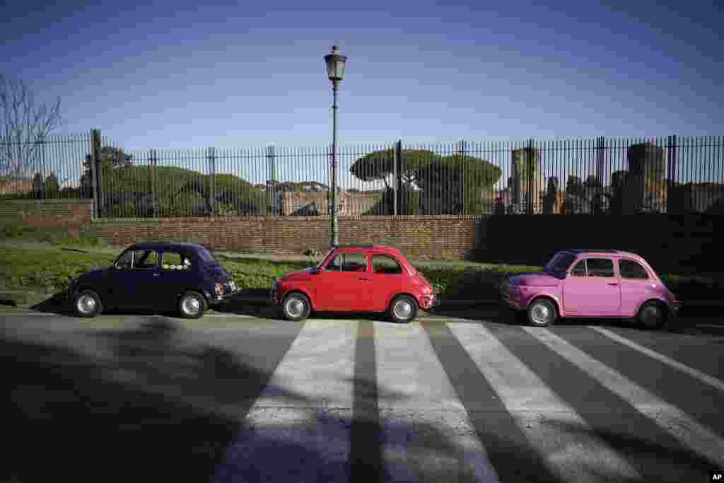Three vintage FIAT 500 cars are parked in front of the ruins of the Ancient Roman Caracalla baths, in Rome, Italy.