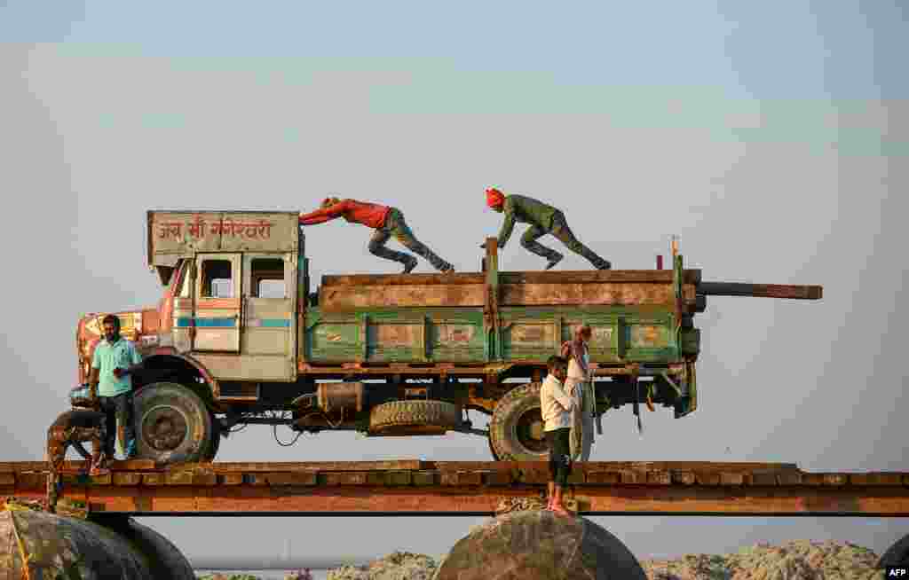 Laborers push wooden boards to construct a temporary pontoon bridge over the Ganges river for the upcoming Hindu festival of Magh Mela in Allahabad, India, Nov. 24, 2019.