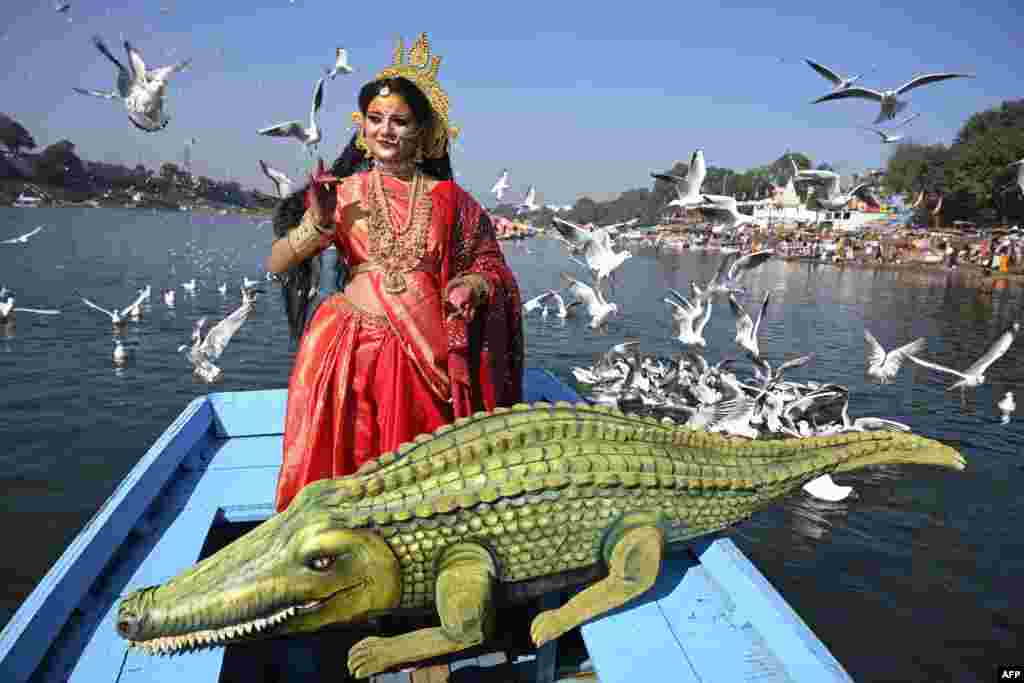 An artist dressed as Goddess Narmada, the river deity named after the Narmada river, accompanied by her vahana (deity's carrier), the crocodile, poses for pictures ahead of Narmada Jayanti celebrations in the Indian city, Jabalpur.