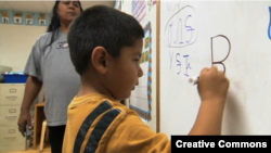 Oklahoma Cherokee language immersion school student writing in the Cherokee syllabary.