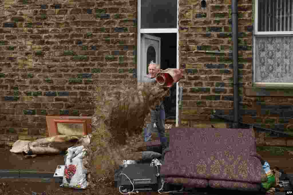 A man empties a bucket of water outside his house in Mytholmroyd, northern England, after flooding brought by Storm Ciara.