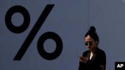 A woman wears Apple AirPods while browsing her iPhone at a popular shopping mall in Beijing, April 4, 2019. The cost of cellphones could increase by $70 in the U.S. if tariffs are put in place.