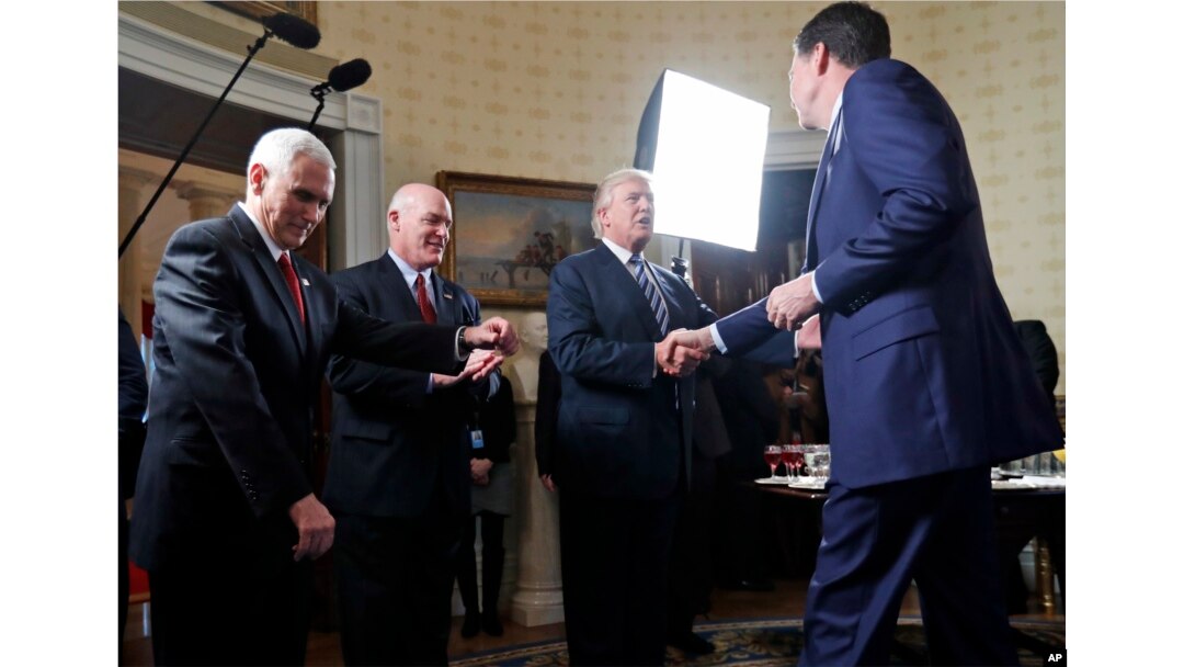 FILE - President Donald Trump (2-R) shakes hands with then-FBI Director James Comey (R) in the Blue Room of the White House in Washington, Jan. 22, 2017, as Vice President Mike Pence (L) and Secret Service Director Joseph Clancy look on. Trump fired Comey in May of that year.