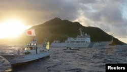 中国海监船51号（中）在东中国海尖阁列岛附近航行，日本海岸警卫队的船只在旁（右），前船为日本渔船。（2013年7月1日）