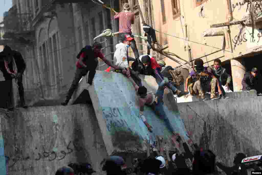 Iraqi demonstrators carry away a man affected by tear gas during the ongoing anti-government protests in Baghdad.