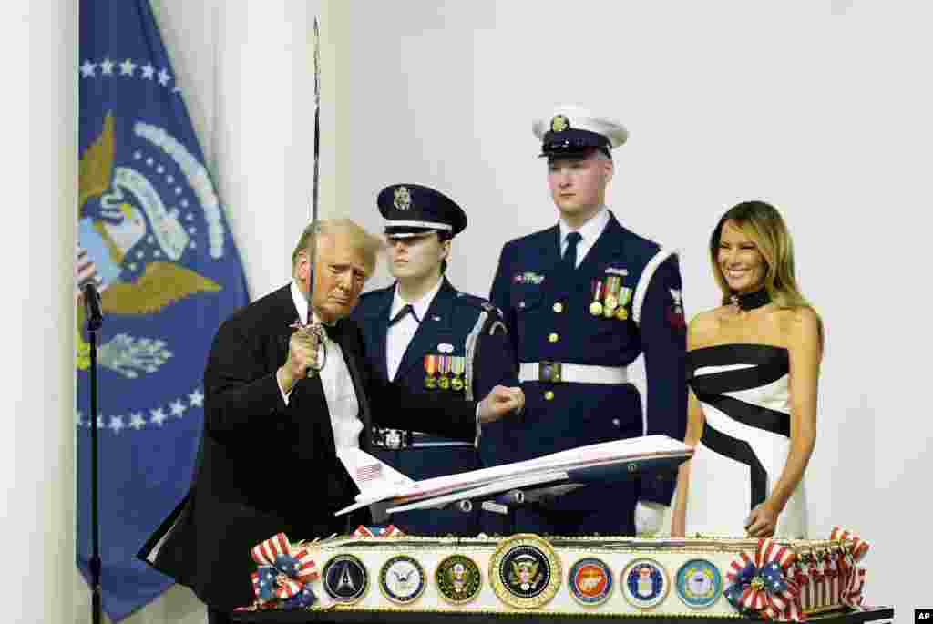 President Donald Trump, left, holds a sabre after cutting a cake as first lady Melania Trump, right, watches at the Commander in Chief Ball on January 20, 2025, in Washington.