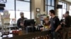 In this photo taken March 20, 2020, Mike Johnston, a clerk at the Maupin Market in tiny Maupin, Oregon, helps a customer while wearing a latex glove to protect himself against the coronavirus.