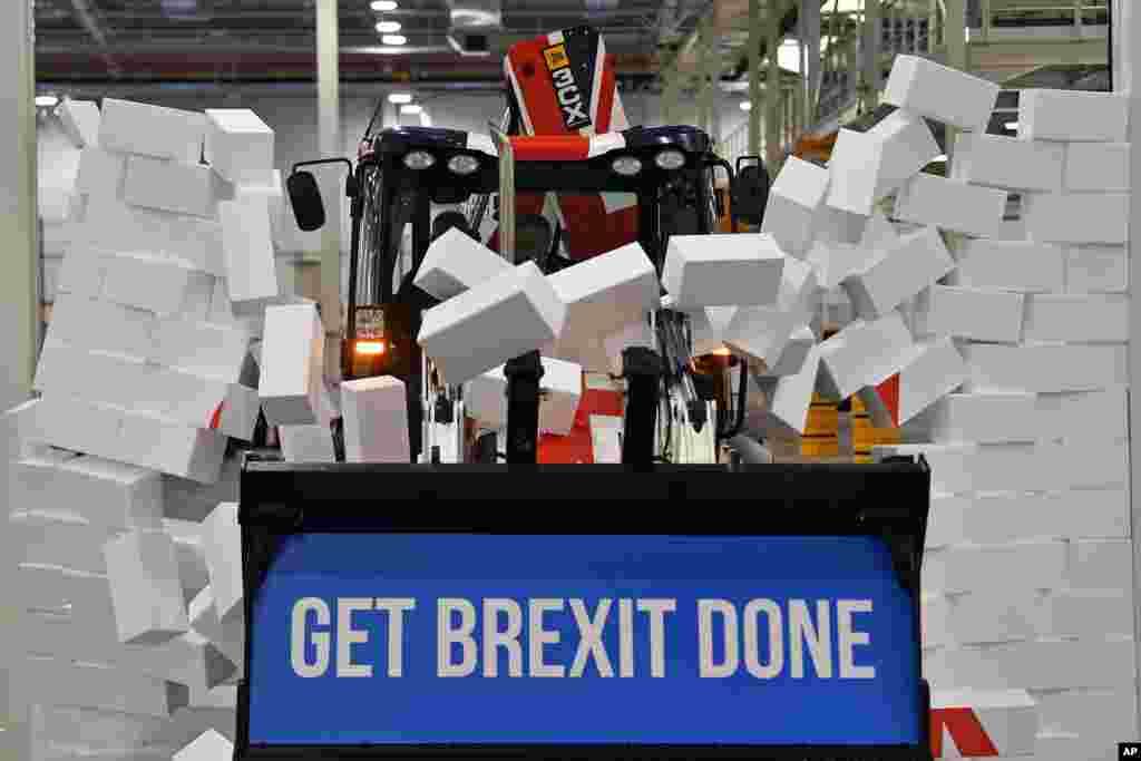 Britain's Prime Minister Boris Johnson drives a JCB through a symbolic wall with the Conservative Party slogan 'Get Brexit Done' in the digger bucket, during an election campaign event at the JCB manufacturing facility in Uttoxeter, England.