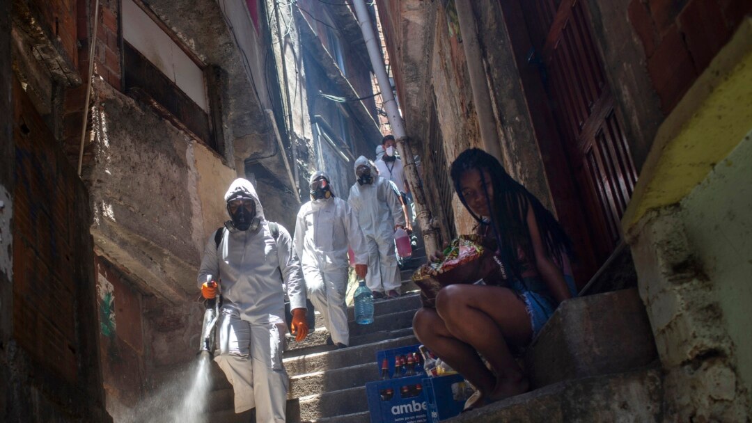 Volunteers spray disinfectant in an alley to help contain the spread of the new coronavirus at the Santa Marta slum in Rio de Janeiro, Brazil, Saturday, Nov. 28, 2020.