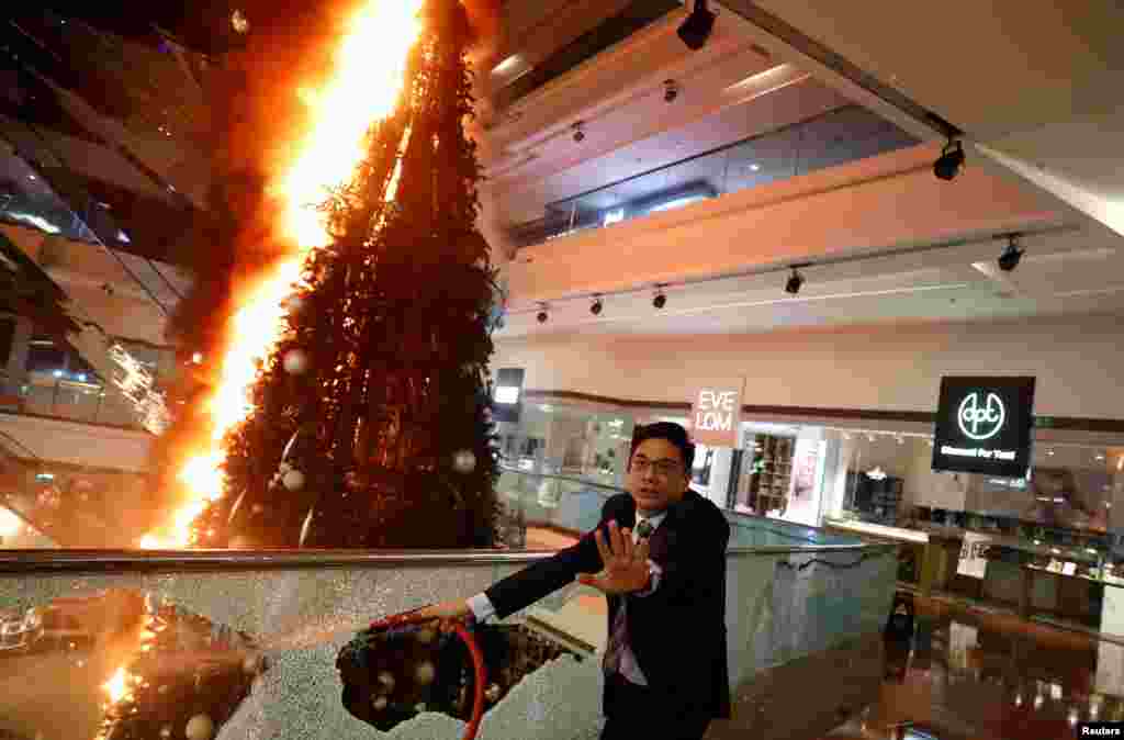 A man reacts as he tries to extinguish a burning Christmas tree at Festival Walk mall in Kowloon Tong, Hong Kong, China.