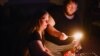FILE - Christina Beverly and John Shearon light candles in their home after winter weather caused electricity blackouts and 'boil water notices in Fort Worth, Texas, Feb. 20, 2021. 
