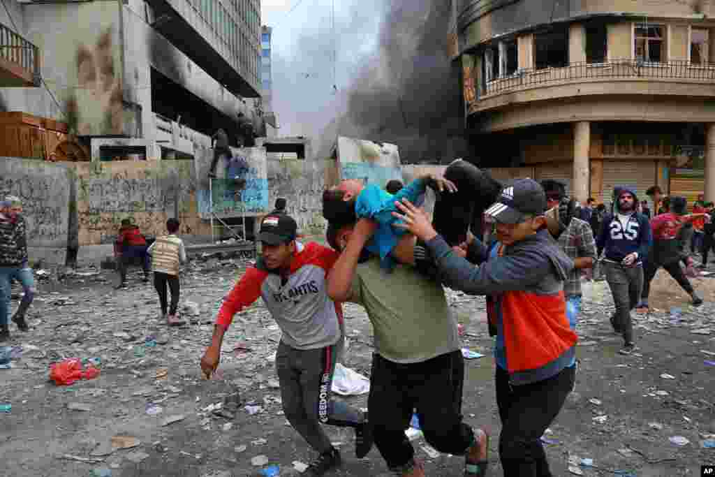 A wounded protester is carried to receive first aid during clashes with security forces on Rasheed Street in Baghdad, Iraq.