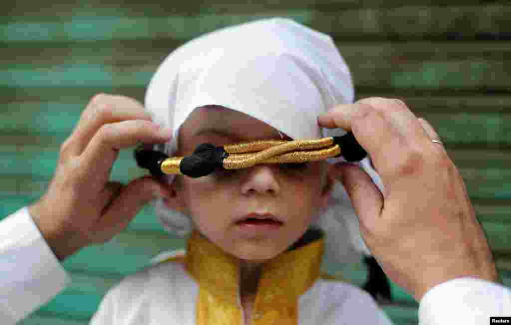 A man adjusts the head gear of his son during a religious procession to mark Eid-e-Milad-ul-Nabi, or birthday celebrations of Prophet Mohammad, in the old quarters of Delhi, India.