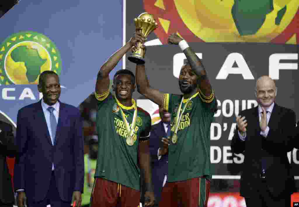 Benjamin Moukandjo, à esquerda e Nicolas Nkoulou com o troféu do CAN 2017, conquistado no Domingo 5 de Fevereiro em Libreville, Gabão. 