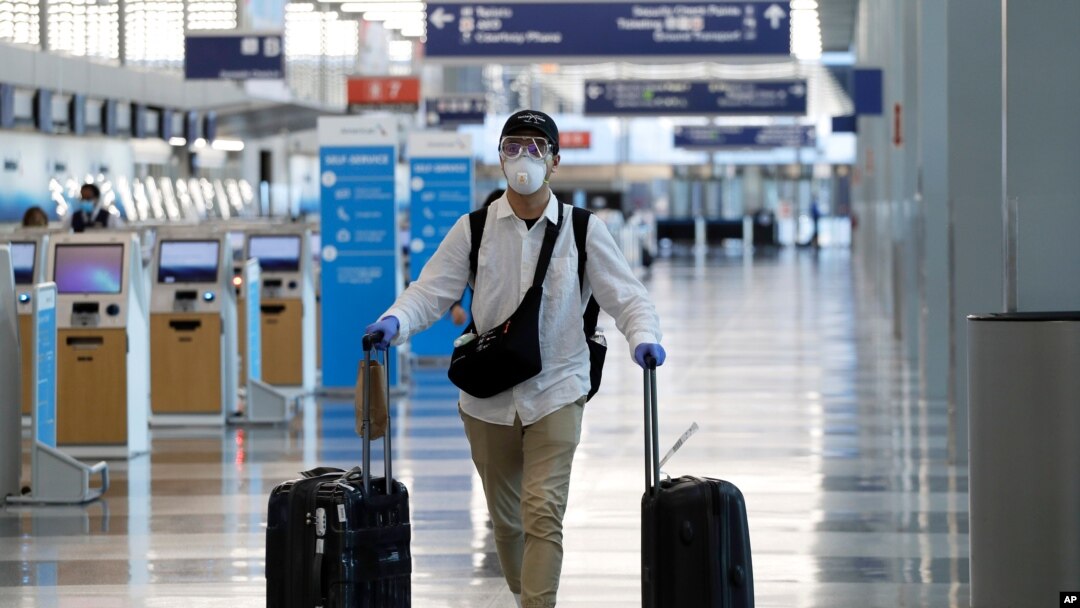 Un viajero usa mascarilla y gafas protectoras mientras camina por la Terminal 3 en el Aeropuerto Internacional O'Hare el martes 16 de junio de 2020 en Chicago.