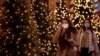 FILE - Women, wearing protective face masks, walk past illuminated Christmas trees in a street in Paris, France, Nov. 12, 2020.