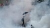 A protester walks in tear gas fired by riot policemen in Hong Kong's financial Central district outside the government headquarters on September 28, 2014.