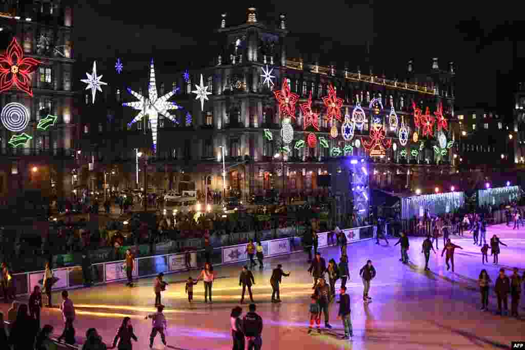 People skate on an acrylic rink placed in the Zocalo square with the City Hall showing Christmas decorations in the background in Mexico City, Dec. 17, 2019.