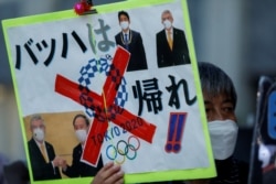 因新冠疫情反對舉辦東京奧運會的民眾在日本首相菅義偉的辦公地點外舉牌要求取消奧運。（2021年7月29日）